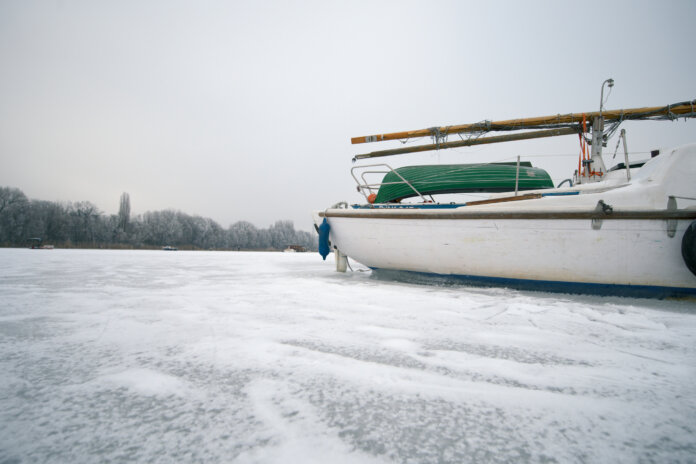 Weißes Boot auf dem eisbedeckten Spreefluss