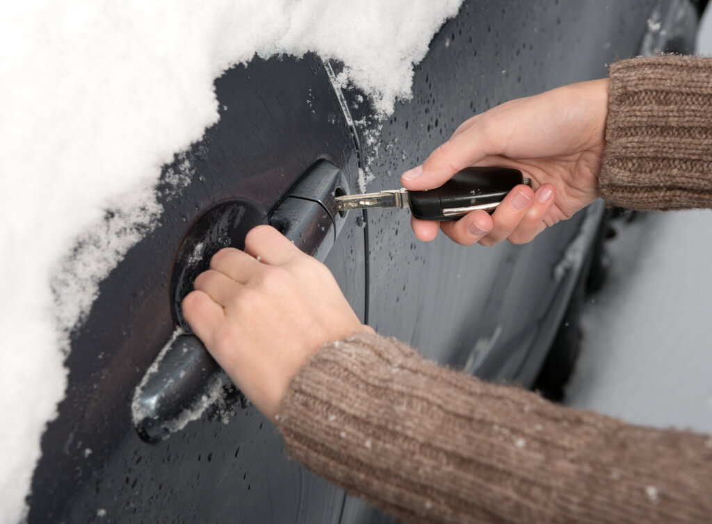 Person versucht gefrorene Autotür zu öffnen